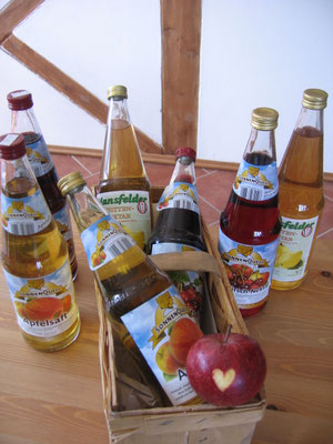 Verschiedene Glasflaschen gefüllt mit Fruchtsäften und ein geschnitzter Apfel mit einem Herz