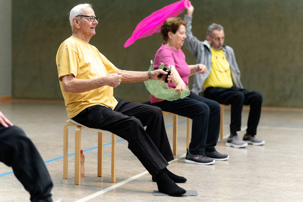 Lungensport beim BSV Achim: Teilnehmende führen im Sitzen Armübungen mit bunten Tüchern und Handtrainern durch.