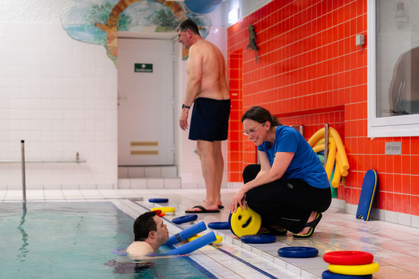 Übungsleiterin begleitet einen Teilnehmer der Schwimmgruppe Belugas individuell am Beckenrand und erklärt die nächsten Übungen.
