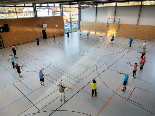 Teilnehmer der Herz- und Rehasportgruppe beim BSV Achim trainieren im Kreis mit Gymnastikringen in der Sporthalle.