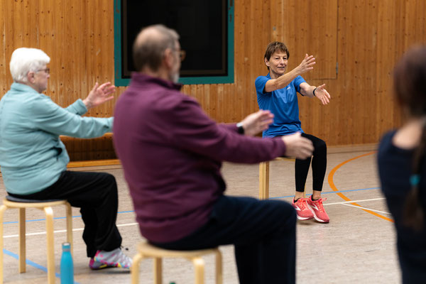 Sitzgymnastik beim Lungensport des BSV Achim: Trainerin leitet eine Übung, Teilnehmende strecken die Arme nach vorne.