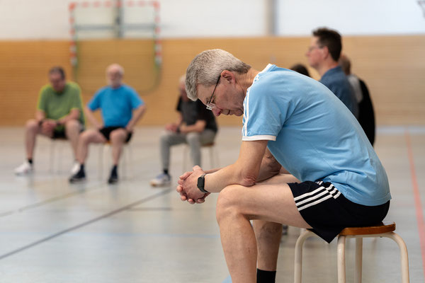 Teilnehmer des Herzsports beim BSV Achim pausiert auf einem Hocker und erholt sich während des Trainings in der Sporthalle.