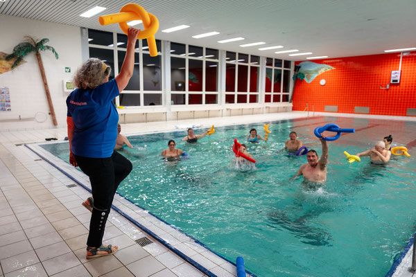 Übungsleiterin der BSV Achim Wassergymnastik-Reha-Sport-Gruppe gibt Übungen am Beckenrand vor, während die Teilnehmenden im Wasser aktiv trainieren.