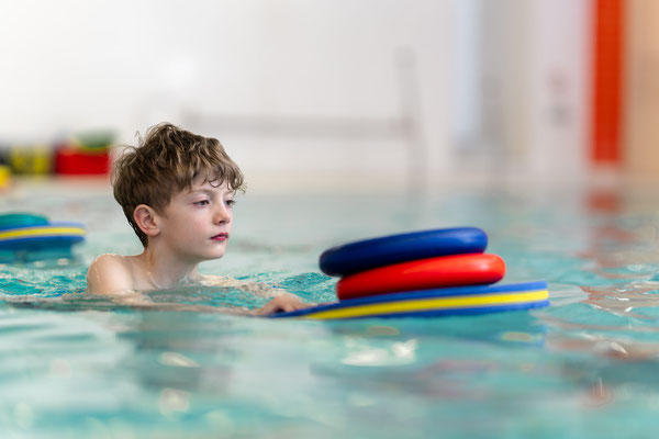 Junge trainiert im Schwimmkurs des BSV Achim mit Schwimmbrett und verbessert seine Wasserlage und Koordination.