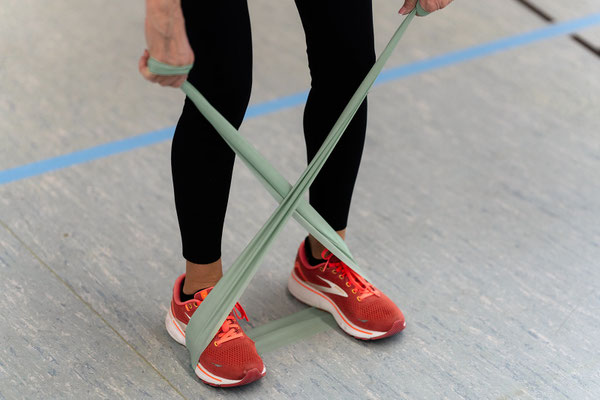 Detailaufnahme einer Übung im Herz- und Rehasport des BSV Achim: Übungsleiterin führt eine Kräftigungsübung mit Theraband im Stand aus.