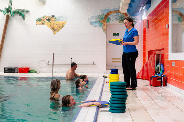 Schwimmkurs Delfine beim BSV Achim mit Trainerin am Beckenrand und Kindern im Hallenbad