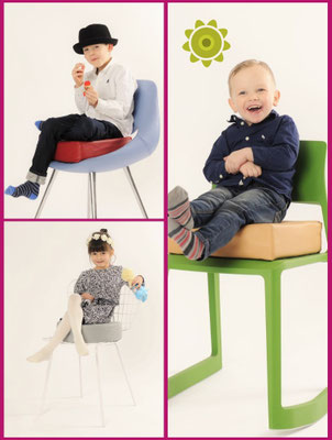 Verschiedene Stühle mit passenden Sitzerhöhungen, auf denen Kinder sitzen