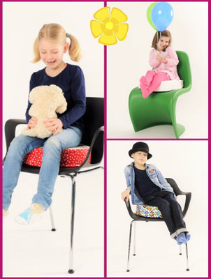 Verschiedene Stühle mit passenden Sitzerhöhungen, auf denen Kinder sitzen