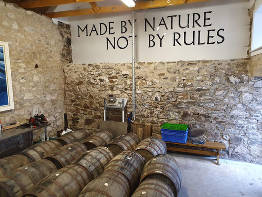 Nc'Nean Distillery Schottland Fässer, das Motto auf einem Schild: "Made by nature not by rules" ©My own Travel