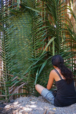 Seraina webt Palmenblätter zu Wanddekoration