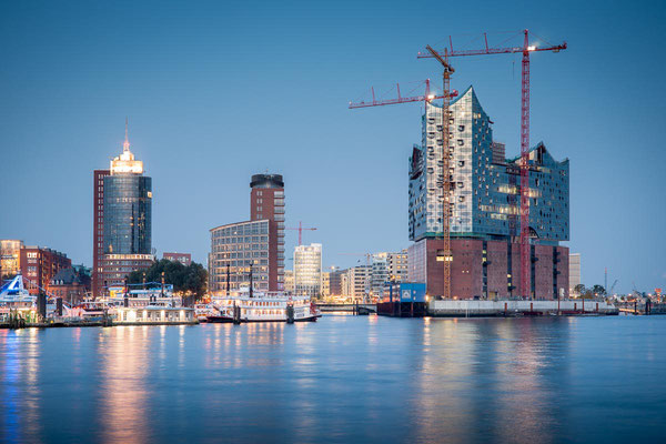 Blick über die Elbe auf Hamburgs Elbphilharmonie im Bau zur blauen Stunde