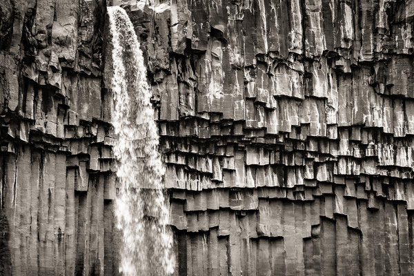 Island: Ein Wasserfall stürzt über eine Wand aus Basaltsäulen