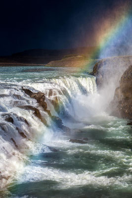 Island: Ein Regenbogen über dem Gullfoss Wasserfall. Am Horizont naht ein Sturm.