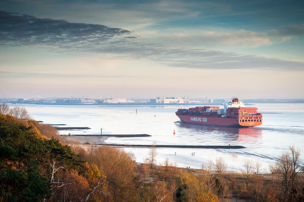 Blick über die Elbe mit Containerschiff und das Airbuswerk am Horizont