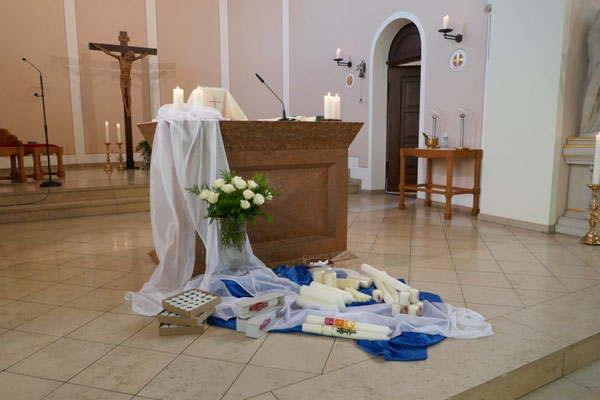 Vor dem Altar sind auf dem Fußboden zahlreiche Kerzen niedergelegt, die heute gesegnet werden sollen.