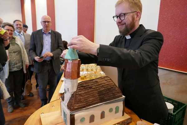 Pfarrer Schmelz schneidet die von Messdienern gebackene Kirche St. Josef an