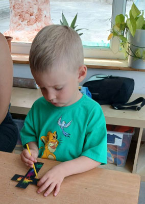 Ein kleiner Junge gestaltet sein Kreuz ganz konzentriert.