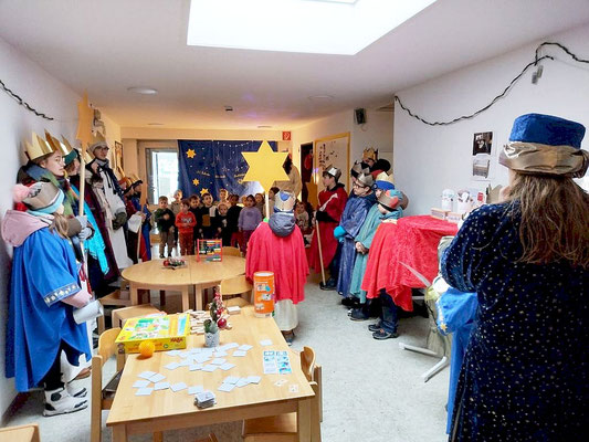 Hier stehen die Sternsinger im Flur des Kindergartens St. Josef, im Hintergrund sind einige Kindergarten-Kinder zu sehen.