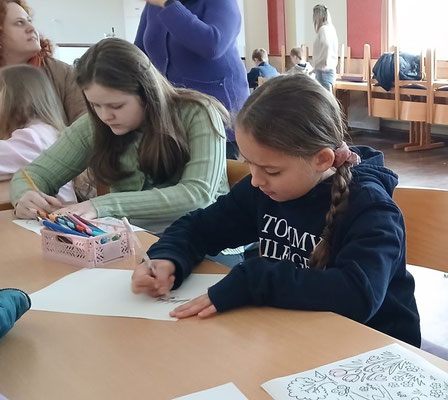 Kinder sitzen am Tisch und malen