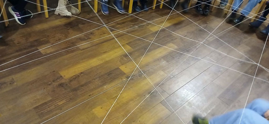 Die Fäden des Wollknäuelspiels stellen eine Verbindung von Kind zu Kind her.