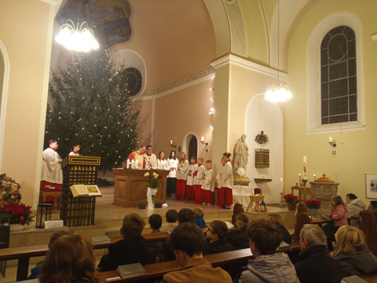 Blick in den Altarraum während der Christmette zeigt die Messdiener und Pfarrer Holger Schmitz am Altar