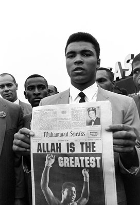 Muhammad Ali, holds a “Muhammad Speaks” newspaper bearing his picture as he and followers leave the Las Vegas convention center after weigh-in ceremonies to defend his title against challenger Floyd Patterson, on Nov. 22, 1965 (AP Photo/Sal Veder)