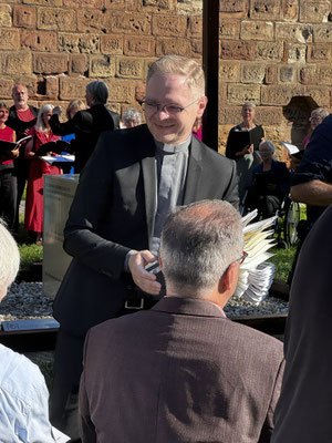 jRöm.-kath. Stadtdekan Andreas Lurz beim Verteilen der Kunstaktions-Papiertüten