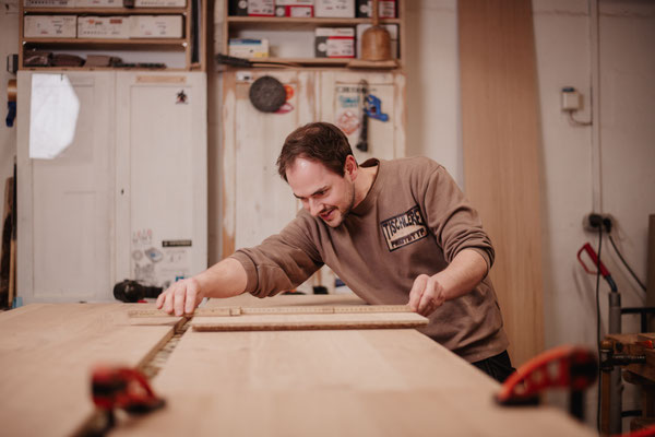 Jan als Werkstattleiter in Aktion in der Werkstatt, misst Platte