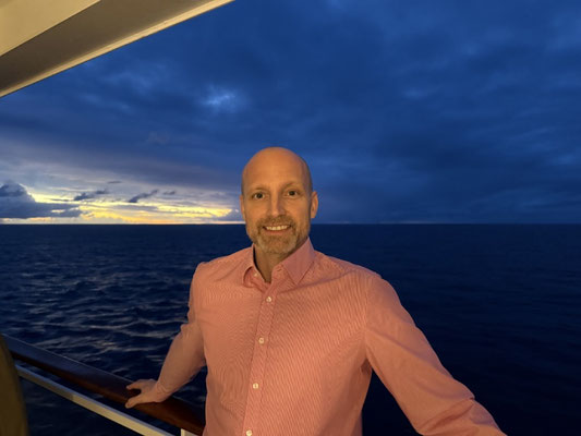 Ein Erwachsener an der Reeling der MS EUROPA 2 am Abend mit Blick aufs Meer