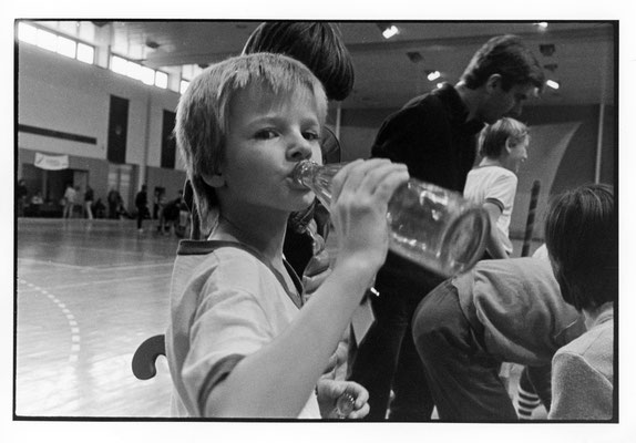 Eine junge Hallenhockey-Spielerin trinkt in einer Spielpause aus ihrer Wasserflasche. Aufgenommen in Berlin-Ost, 1987.