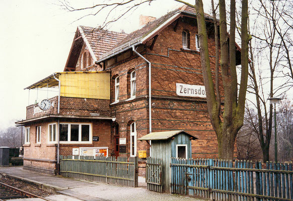 1983: Bahnhofsgebäude von Westen mit Sperrenhäuschen, Holzzaun, Stellwerk und Terrasse (Aufnahme: Schrobitz, Zernsdorf)