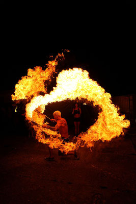 Veranstaltungsfotograf bei einer Feuershow, Eventfoto zeigt Mann mit Feuerkreis