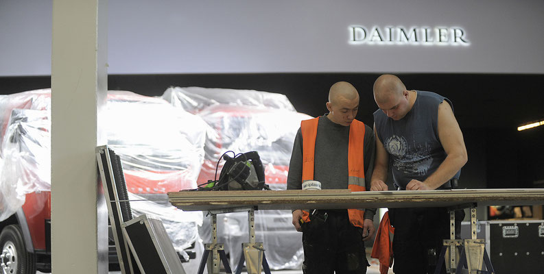PR-Foto zweier Männer, die auf der Hannover Messe Nutzfahrzeuge einen Messestand bauen