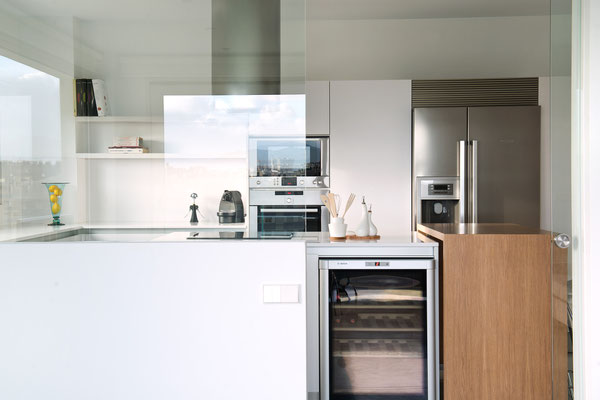 Cocina blanca, con electrodomésticos en acero.