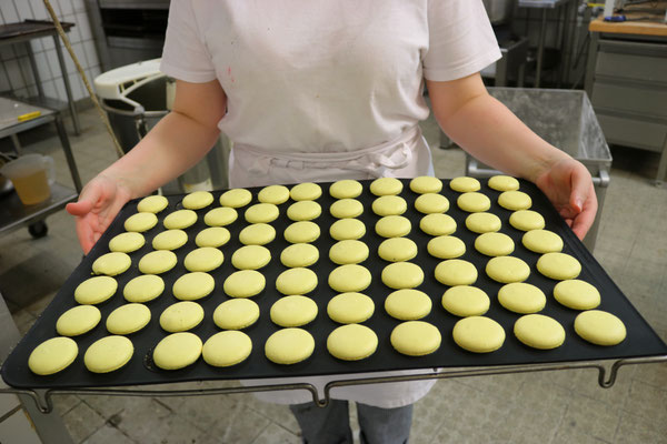Mitarbeiter mit Macarons frisch aus dem Ofen