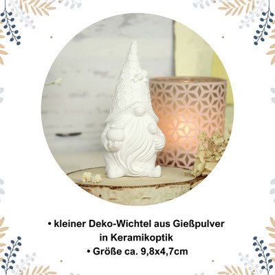 Kleiner weißer Deko-Wichtel neben leuchtender Kerze, umgeben von floralen Elementen.