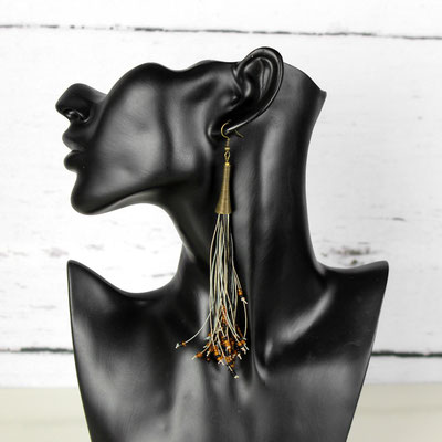 Schwarze Schaufensterpuppe mit langem, bronzefarbenem Quastenohrring.