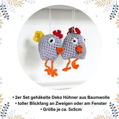 Zwei gehäkelte Deko-Hühner aus Baumwolle, hängend an Fäden als Frühlingsdeko vor einem Fenster.