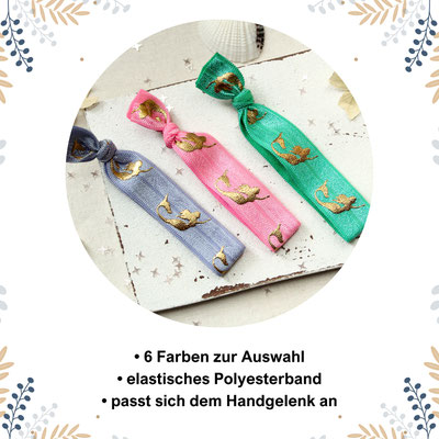 Drei elastische Armbänder in Blau, Rosa und Grün mit goldenen Meerjungfrauenmotiven auf einem Hintergrund mit Sternen.