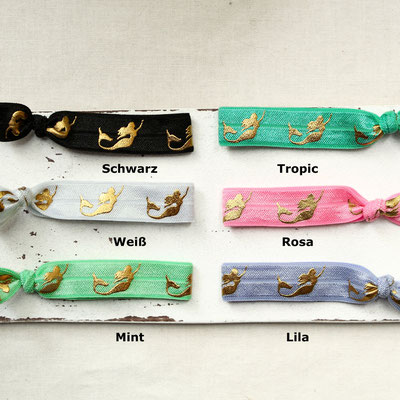 Sechs Haargummis mit goldenen Meerjungfrauen in verschiedenen Farben: Schwarz, Tropic, Weiß, Rosa, Mint, Lila.