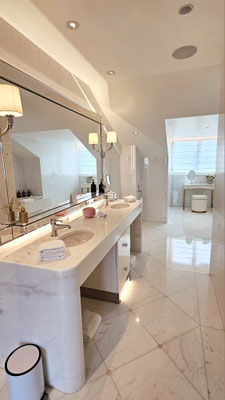Salle de bain chic et fonctionnelle à l'hôtel The Woodward, dotée de matériaux nobles comme le marbre et des accessoires roses, créant une ambiance intemporelle et luxueuse.