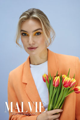 blonde frau mit orangenen tulpen orangenem blazer gelbes Augenmakeup