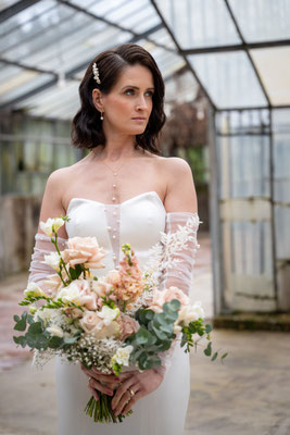 Model mit elegantem hochzeitskleid und Brautstrauß im Gewächshaus Langenfeld