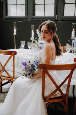 braut in kleid mit blumenstrauss am gedeckten tisch 