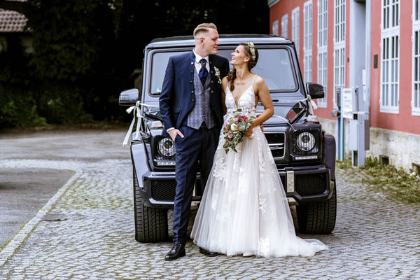 Brautpaar steht vor Auto