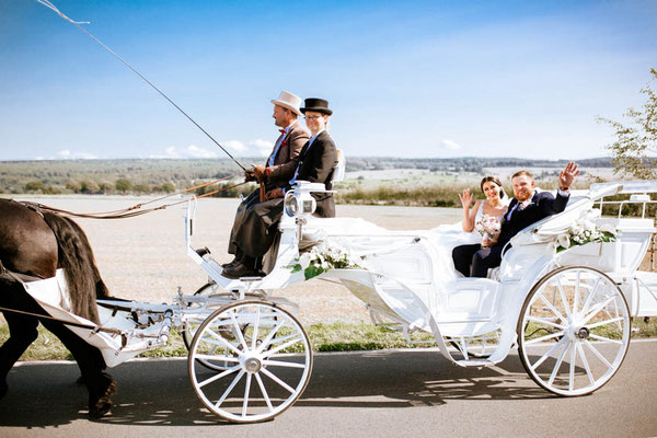Brautpaar fährt in Hochzeitskutsche