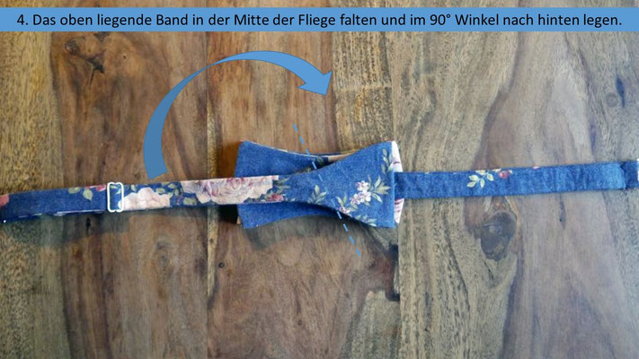 Schritt 4 der Schritt für Schritt Anleitung zum Fliege selbstbinden - Das oben liegende Band in der Fliegenmitte falten und im 90° Winkel nach hinten legen