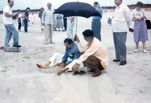 Meher Baba on Center Beach ( Arcadia Beach ) at Myrtle Beach, Sc. Eruch Jessawala holding the umbrella and Lud Dimpfl looking on. Meherjee Karkaria standing behind. Don Stevens on the far left. Image captured by Anthony Zois from a film by Sufism Reorien