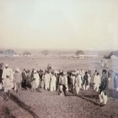 A procession leading Meher Baba up the hill at Meherabad, with lower Meherabad in the far background.