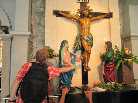 Begeisterter Tourist ahmt die gläubigen Eingeborenen nach und berührt eine Heiligenfigur. (Basilica Minore del Santo Nino)